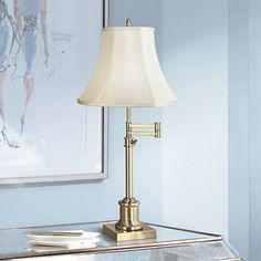 a lamp is sitting on a table next to a framed fashion illustration in a blue room