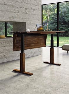 a desk with a laptop on it in front of a large glass window that looks out onto the outdoors