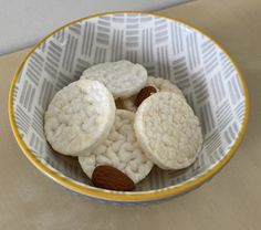 four cookies in a bowl with almonds on the top and one is cut in half