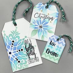 three tags that say christmas and have blue flowers on them with green string attached to the tags