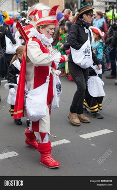 people in costume walking down the street during a parade with many onlookers