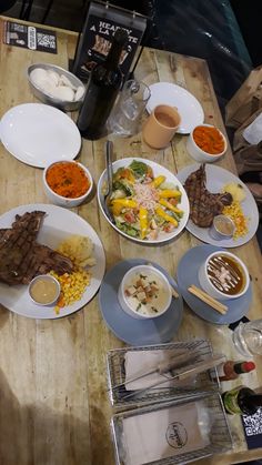 a wooden table topped with lots of plates and bowls filled with different types of food