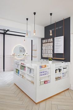 a white counter in a store with lots of bottles on it and lights hanging from the ceiling