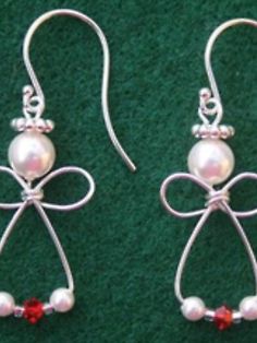 two pairs of earrings with bows and pearls on them, sitting on a green surface