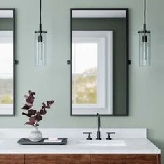 a bathroom vanity with two mirrors above it and a vase filled with flowers on the counter