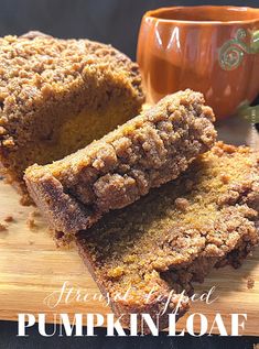 a loaf of pumpkin bread sitting on top of a cutting board next to a cup