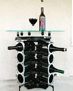 a wine rack made out of bottles and glasses on top of a glass table with a bottle in the middle