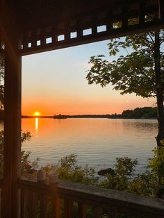 the sun is setting over a lake with trees