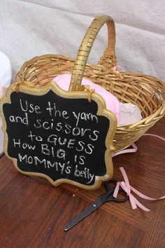 a basket with a sign that says use the yarn and scissors to guess how big is mommy's baby