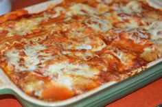 a cheesy pizza in a green casserole dish on an orange counter