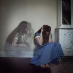 a woman sitting on the floor with her head in her hands