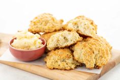 biscuits and mashed potatoes on a cutting board with a small bowl of sauce in the middle