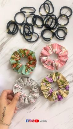 several different types of hair ties on a white marble table with one being held up by a hand