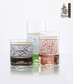 three glasses with arabic writing on them sitting next to each other in front of a white background