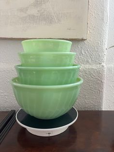 a stack of green bowls sitting on top of a wooden table