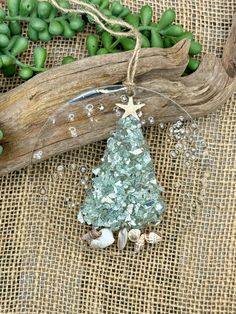 a christmas tree ornament hanging from a wooden branch with sea glass on it