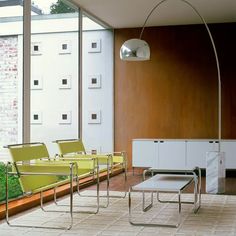 a living room filled with lots of furniture and large glass windows on the side of it