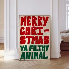 a merry christmas sign is on the floor in front of a white wall and wooden floors