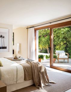 a bedroom with sliding glass doors leading to an outside deck area and palm trees in the background