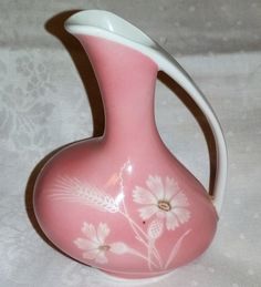 a pink vase with white flowers painted on it