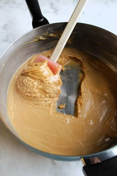 a person mixing peanut butter in a bowl with a spatula on the counter top