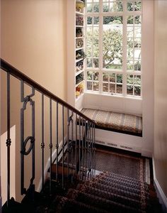 the stairs lead up to an open window in a home's entryway, which also has a bench on one side