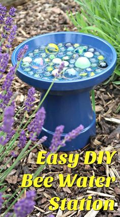 a blue bird bath sitting on the ground next to purple flowers and lavenders with text that reads, easy diy bee water station