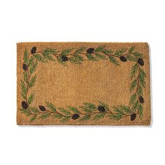 a door mat with pine cones and evergreen needles on the border, in front of a white background