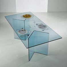 a glass table that has some food on it in front of white walls and flooring