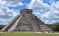 people walking around an ancient pyramid on a sunny day