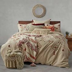 a bedroom with a large bed covered in beige blankets and pillows, next to a small basket