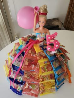 a barbie doll holding a pink balloon on top of a pile of toys