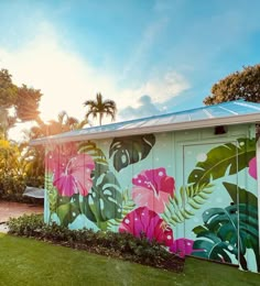 a colorfully painted building with palm trees and flowers on it's exterior wall