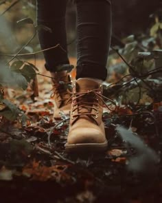 a person wearing brown boots walking through leaves