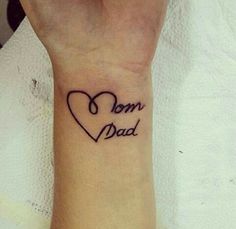 a wrist tattoo with the words mom and dad written on it