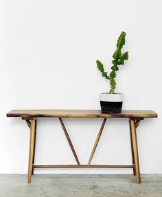 a wooden bench with a potted plant on it's top and bottom shelf