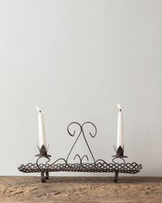 two white candles sitting on top of a wooden table