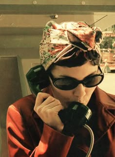 a woman wearing sunglasses and a cat hat talking on the phone