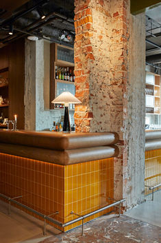 an empty bar with yellow tiles on the floor and brick walls in front of it