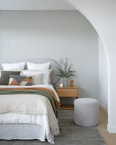 a bedroom with a bed, nightstands and pillows on the floor in front of a striped wall