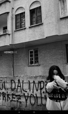 a woman standing in front of a building with graffiti on it