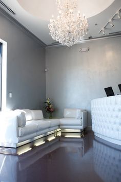 a living room with white couches and a chandelier hanging from the ceiling