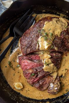 steak and gravy in a cast iron skillet with utensils on the side