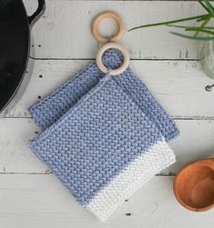 a crocheted dish cloth and wooden spoon on a white wood table with a pot holder