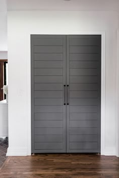 an empty room with two gray doors and hard wood flooring