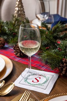 a glass of white wine sitting on top of a table next to gold utensils