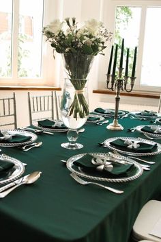 a table set with place settings and flowers in a vase on the centerpieces