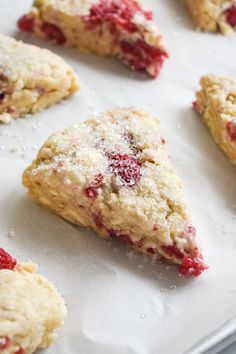 strawberry scones on a baking sheet with powdered sugar and cranberry sauce