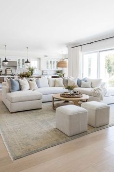 a living room with white couches and pillows on top of a rug in front of a large window