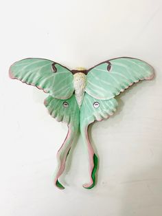 a green and pink butterfly hanging on the wall